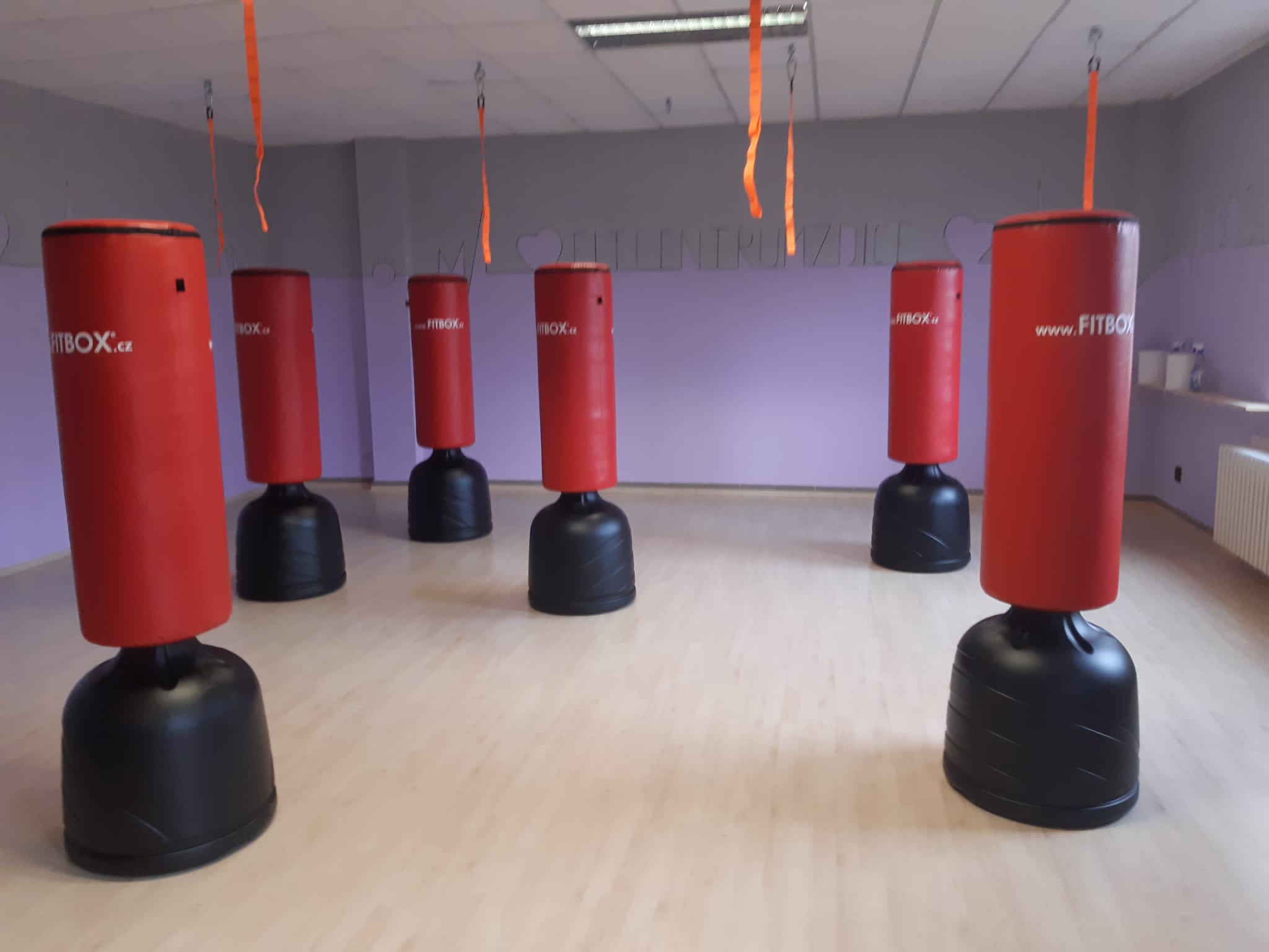 Interiér fitcentra s červenými fitbox totemy.